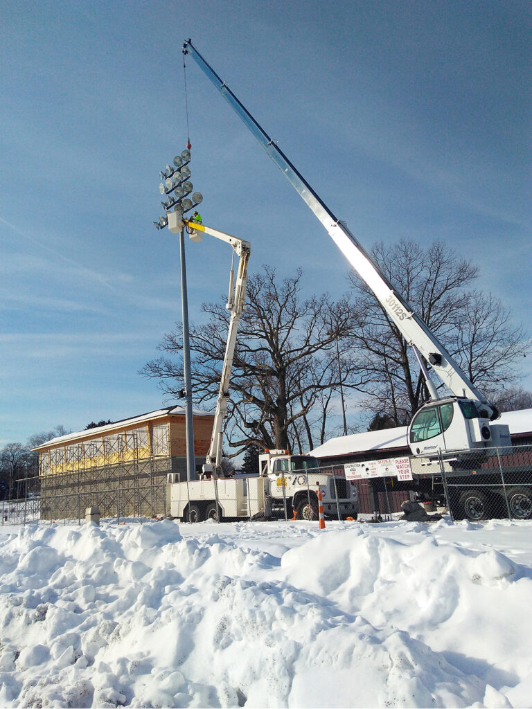 Stadium Lights being worked on by an electrician and a boom truck.